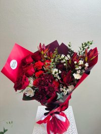Velvet Flame is a dramatic arrangement of roses, chrysanthemums, and waxflowers in red and burgundy tones.