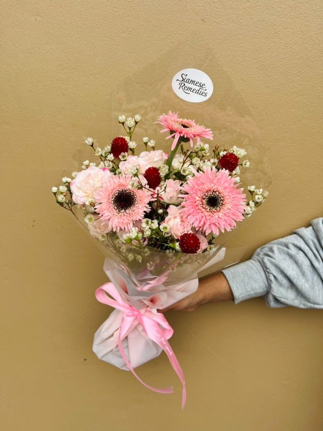 Bouquet with pink gerberas, pink roses, white wax flowers, and red gomphrena.