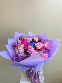 A lush bouquet featuring roses, carnations, lisianthuses, and hydrangeas in pink, purple, and blue hues.