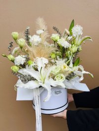 Pure white lilies, lisianthus, carnations, queen anne’s lace, eucalyptus, and soft pampas grass in a white hat box.