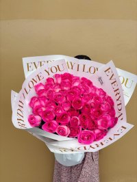 A bouquet of 50 dark pink roses wrapped in white paper with golden lettering.