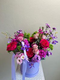 A bold floral box with red and pink roses, purple orchids, carnations, and chrysanthemums.