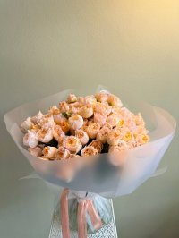 A full peach rose bouquet wrapped in translucent white paper and tied with blush satin ribbon.