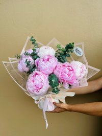 Bouquet of 7 blooming pink peonies, cradled in soft eucalyptus and wrapped in translucent pastel layers.
