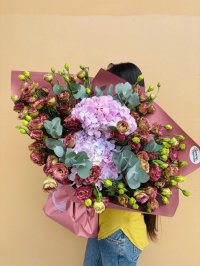 A large burgundy-wrapped bouquet of lavender hydrangeas and plum lisianthuses.