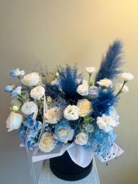 A refined floral box with white roses, blue lisianthuses, hydrangeas, and dry flowers.