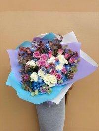 A bouquet of pastel roses and blue hydrangeas with rustic foliage, wrapped in lilac and sky-blue paper.