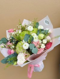 A charming bouquet with pink lisianthuses, carnations, white chrysanthemums, and wax flowers.