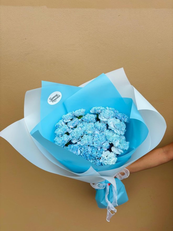 A bouquet of blue-tinted carnations wrapped in sky-blue paper.