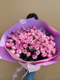 A large bouquet of violet roses wrapped in lavender and blush pink paper, symbolizing love and elegance.