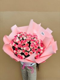 A large bouquet of pink and white roses beautifully arranged in pink wrapping.