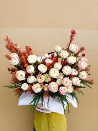 A dramatic bouquet of creamy white roses with crimson accents and greenery, arranged in a wide round display.
