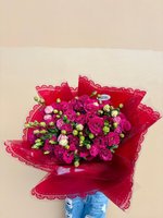 Bouquet of vibrant pink and red roses with green buds wrapped in ornate red lace