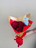 Mini Me bouquet featuring eight deep red burgundy roses wrapped in gold and red paper with red ribbon, held against white background