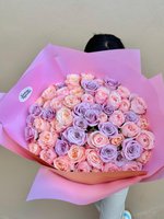 Lilac, blush, and peach rose bouquet wrapped in pastel pink paper.