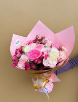 A pink bouquet featuring roses, carnations, lisianthuses, and asters wrapped in pink and gold paper.