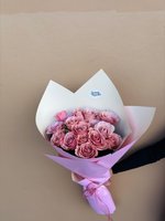 Hand holding Estelle bouquet of 14 pink roses in various shades wrapped in white and pink paper with pink ribbon