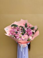 A large bouquet of pink lilies, carnations, and lisianthus with eucalyptus wrapped in blush pink paper.
