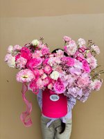 Luxury red box arrangement featuring pink and white lisianthus, carnations, and ranunculus with delicate wax flowers, held by person in white shirt