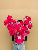 Bright fuchsia pink flower arrangement with roses and spray roses in a matching pink hat box.