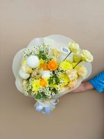 Hand-held Fairy bouquet with white and yellow chrysanthemums, cream roses, orange ranunculus, and white baby's breath wrapped in white paper with r...