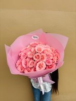 Bouquet of lush pink roses wrapped in soft pink paper.