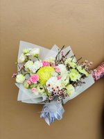 A soft pastel bouquet featuring pink carnations, yellow chrysanthemums, and white roses with wax flowers.