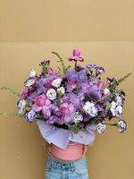 Purple Parade bouquet held by person in pink shirt and jeans, featuring purple orchids, pink roses, white and purple lisianthus, and purple statice...