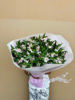 Hand-tied bouquet of white and pale pink alstroemeria flowers with green foliage, wrapped in white paper with pink and white ribbons