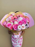Rita bouquet held by person wearing pink floral dress, featuring pink and white lisianthus flowers with white chrysanthemums wrapped in pink and go...