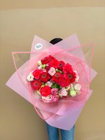 Bouquet of hot pink gerberas, carnations, ranunculus, and pastel roses wrapped in pink paper.