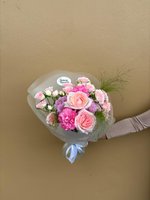 Pink and white rose bouquet with lilies and orchids, wrapped in soft paper and tied with a ribbon.