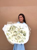 White rose bouquet with daisies held by a person in a blue dress.