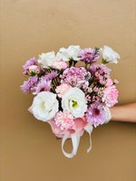 Bouquet with white lisianthus, lavender chrysanthemums, and pink carnations wrapped in blush paper.
